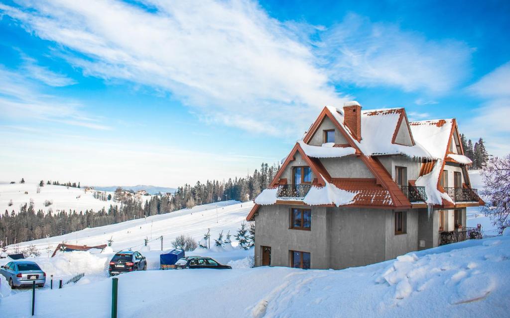 una casa cubierta de nieve en una ladera cubierta de nieve en Gliczarowski gościniec, en Gliczarów Górny