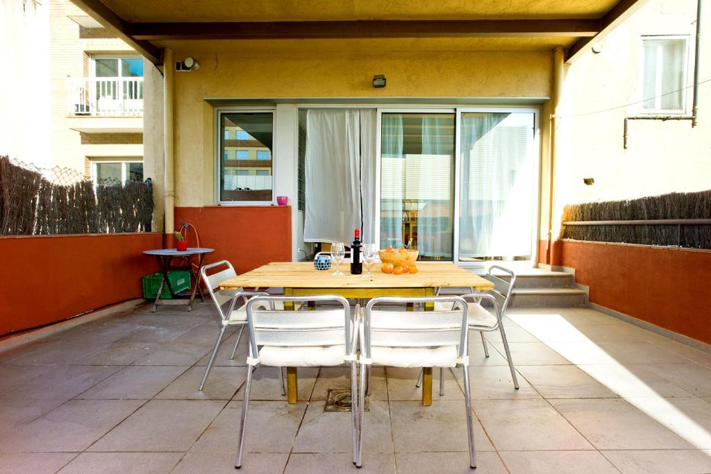 uma mesa de madeira e cadeiras num pátio em Amplio apartamento con terraza en zona muy tranquila em Barcelona