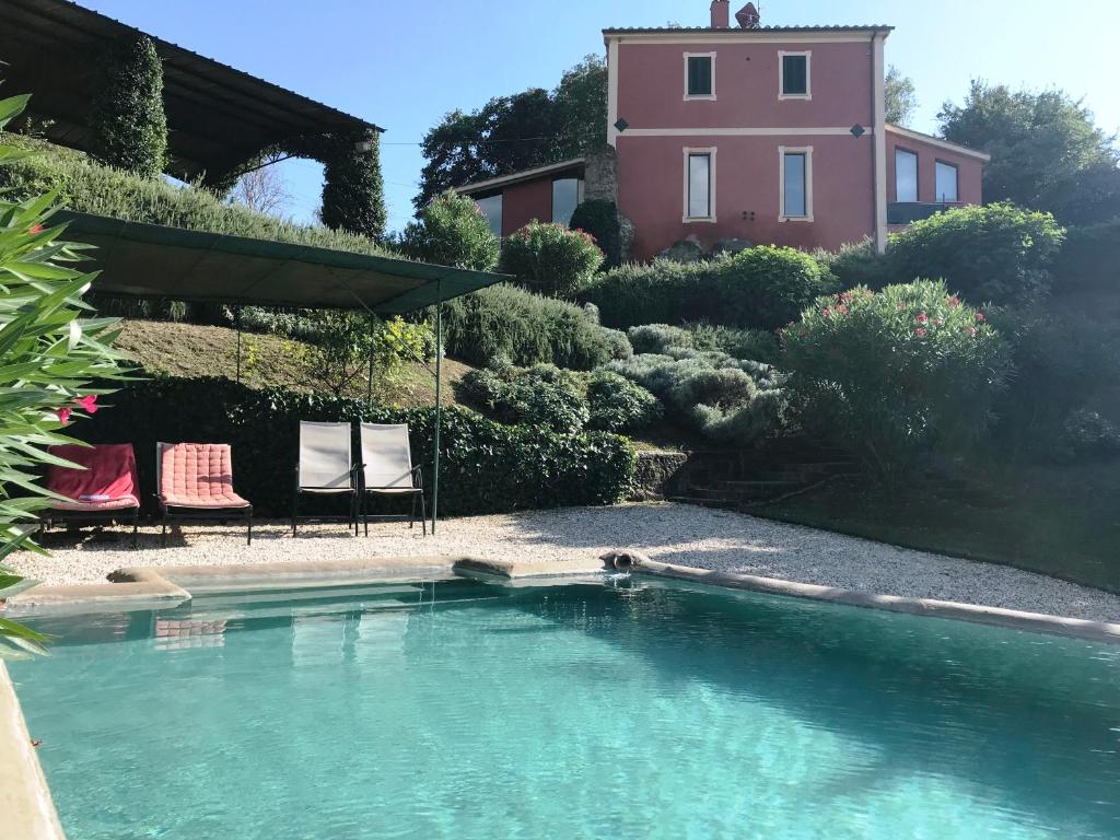 einen Pool mit zwei Stühlen und ein Haus in der Unterkunft La casa rossa sull'arco romano in Otricoli