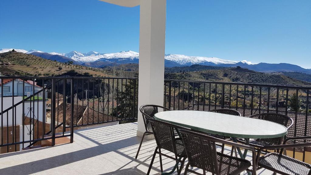 a balcony with a table and chairs and mountains at Villa Cuesta Colorada in Huétor Santillán