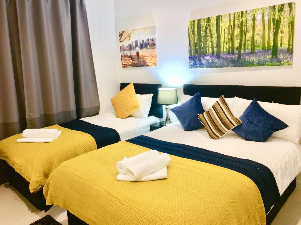 a bedroom with two beds with yellow and blue sheets at Dockland Excel 2 Bedroom Apartment in London