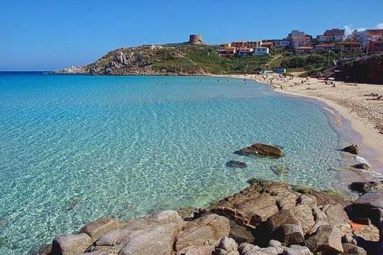 a beach with a group of people in the water at Appartamenti Lungoni in Santa Teresa Gallura
