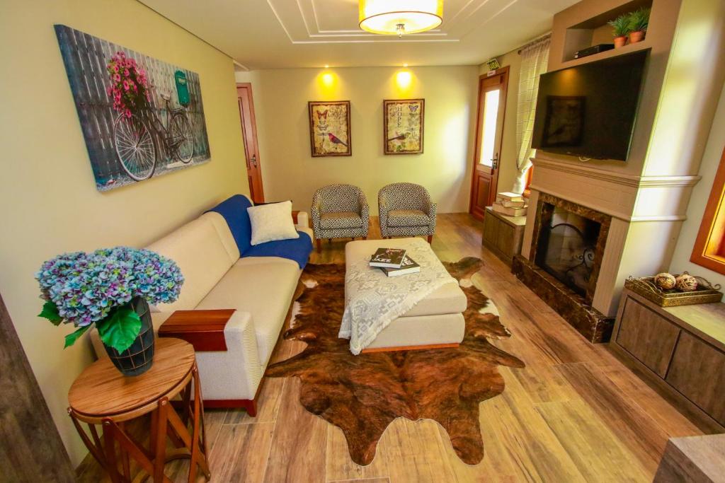 ein Wohnzimmer mit einem Sofa und einem Kamin in der Unterkunft Pousada Caminho dos Plátanos in Gramado