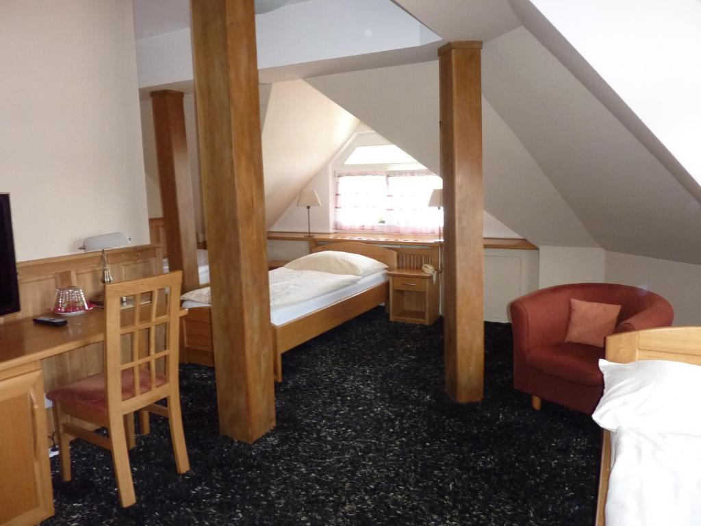 a attic room with a bed and a chair at Hotel & Restaurant Na Fryštátské in Karviná