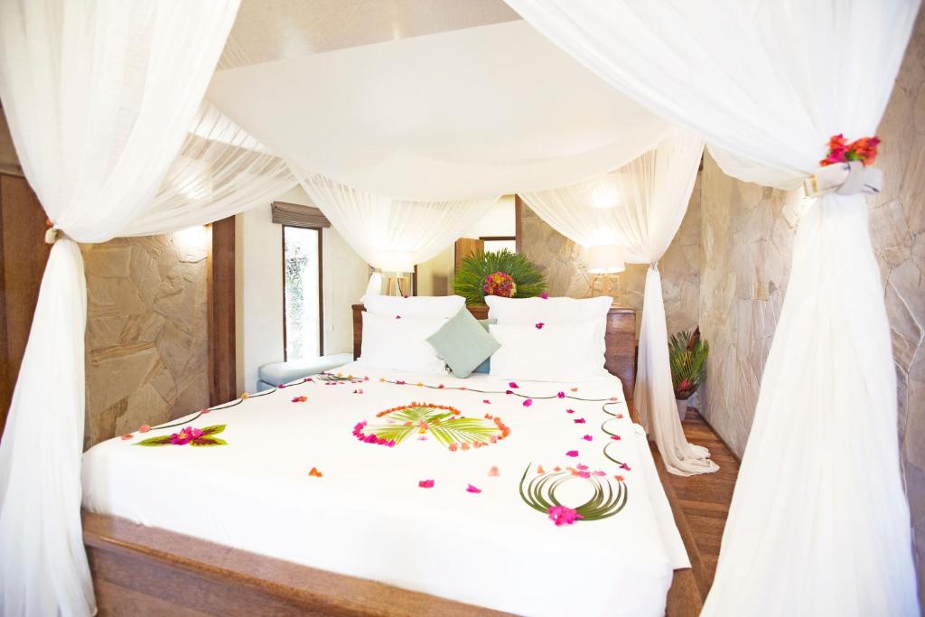 a bedroom with a white bed with flowers on it at Tulia Zanzibar Unique Beach Resort in Pongwe