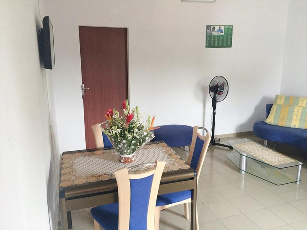 uma mesa de jantar e cadeiras com um vaso de flores em Hotel Marie Antoinette Lome em Lomé