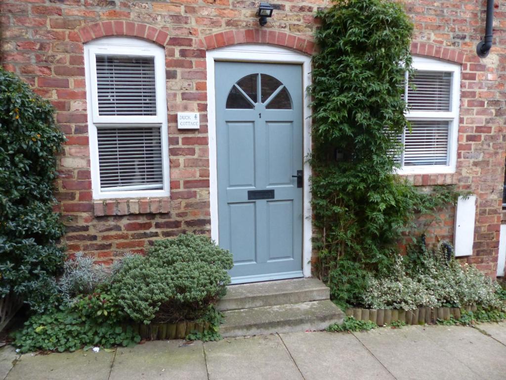 a blue door on a brick house at Duck Cottage in Thirsk