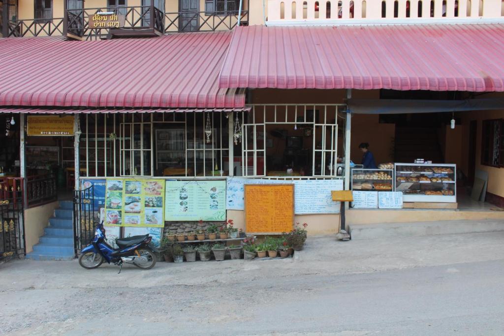 uma loja com um telhado vermelho e uma scooter estacionada em frente em Pakbeng Guesthouse em Pakbeng