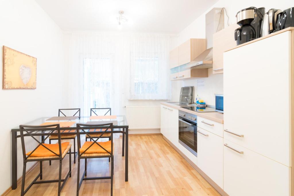eine Küche mit weißen Schränken sowie einem Tisch und Stühlen in der Unterkunft Private apartments with direct subway entrance in Fürth