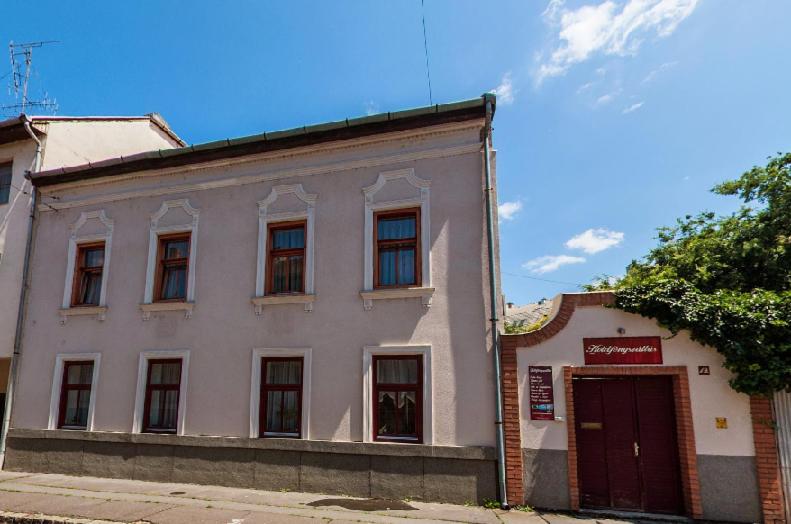 a white building with a red door on a street at Holdfényszállás in Szeged