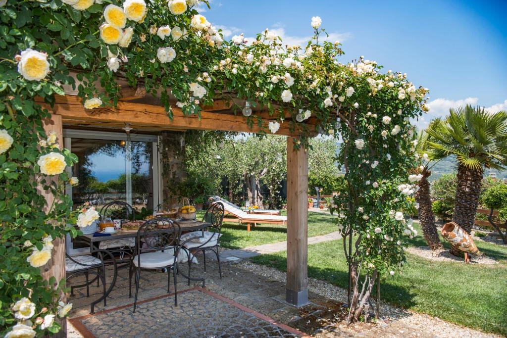 a wooden pergola with a table and flowers at Villa Annetta in Poggi