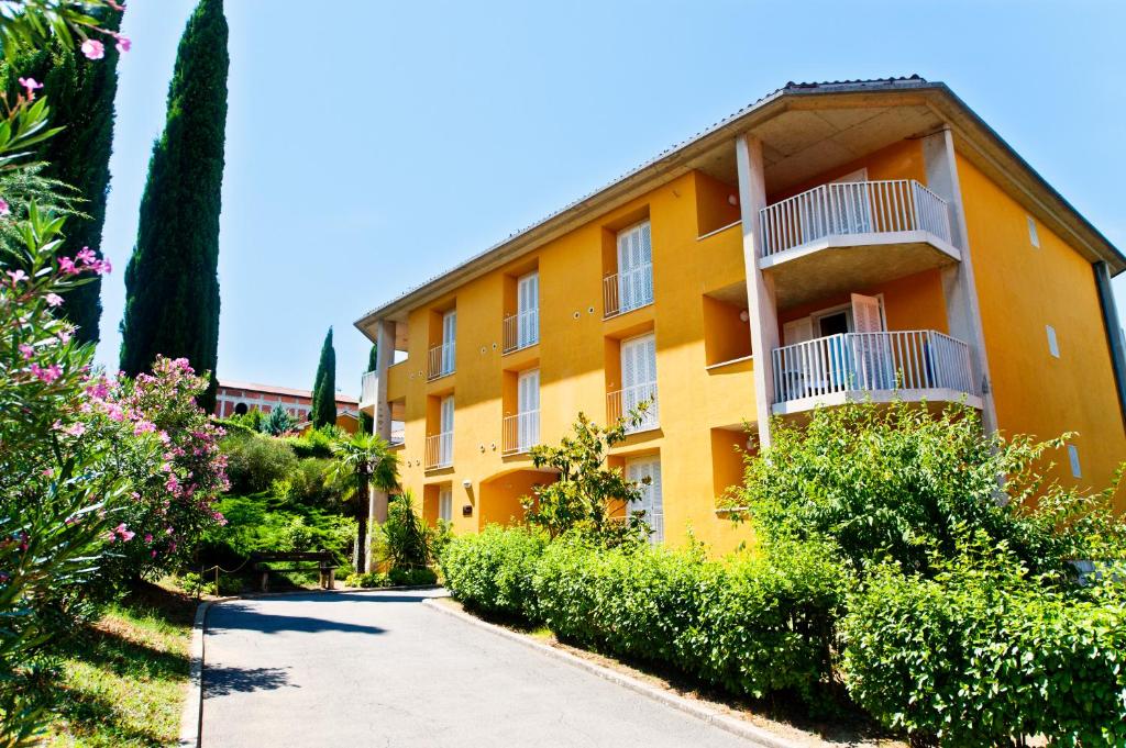 an orange building with a balcony and bushes at Dependences - San Simon Resort in Izola