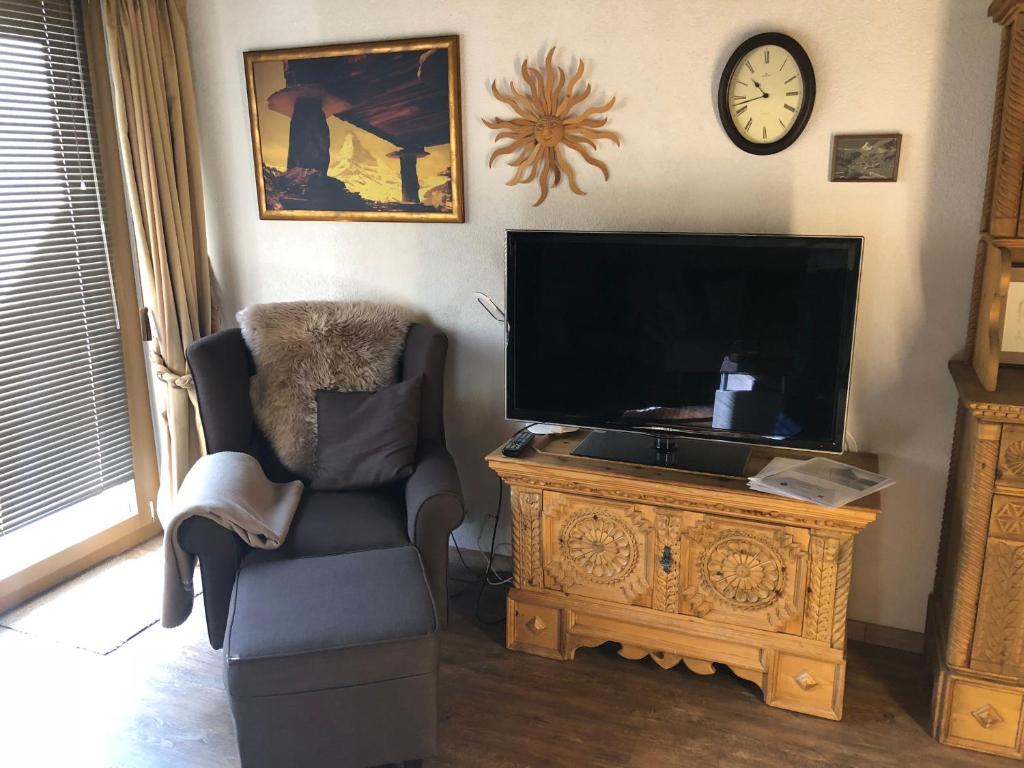 a living room with a chair and a flat screen tv at Chalet Memory in Zermatt