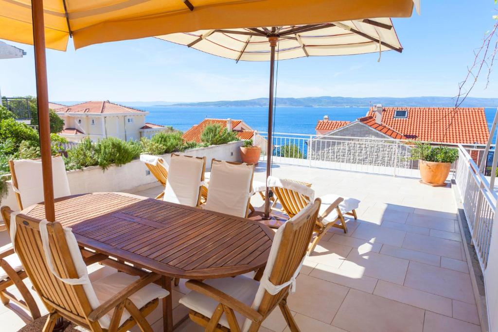 einen Holztisch und Stühle auf einem Balkon mit Sonnenschirm in der Unterkunft Guesthouse Mate Ledic in Brela