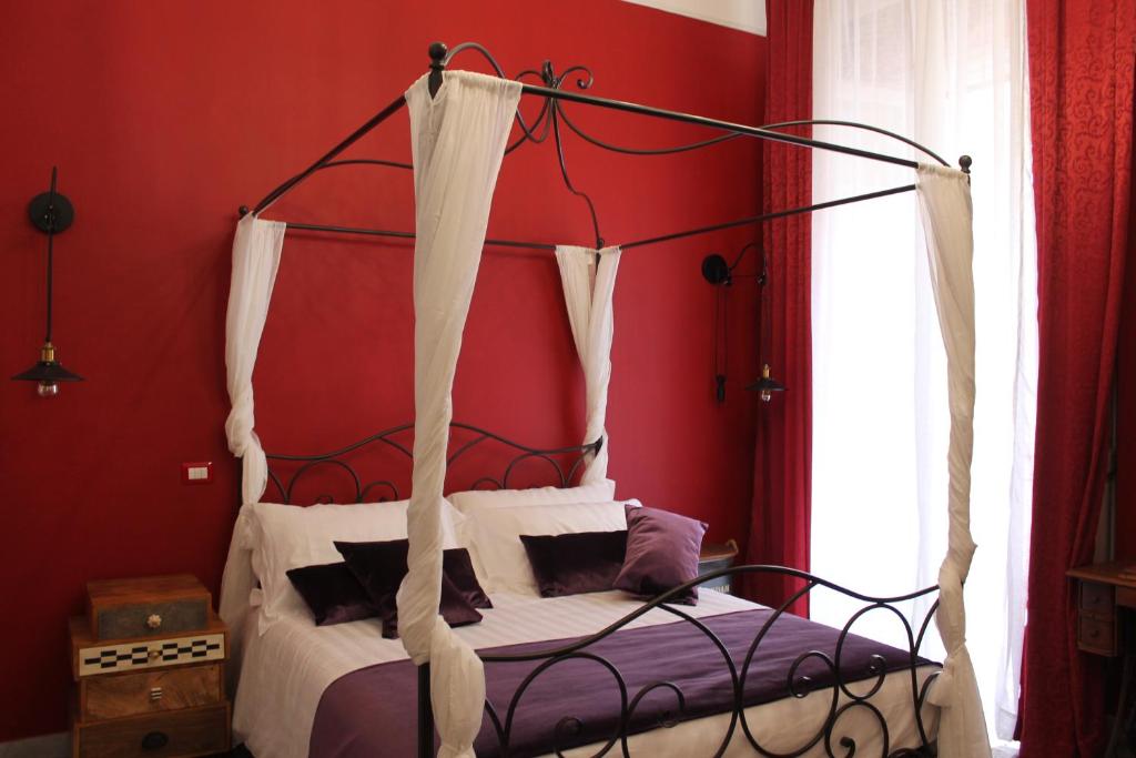 1 dormitorio con cama con dosel y paredes rojas en Lavanera Home, en Nápoles