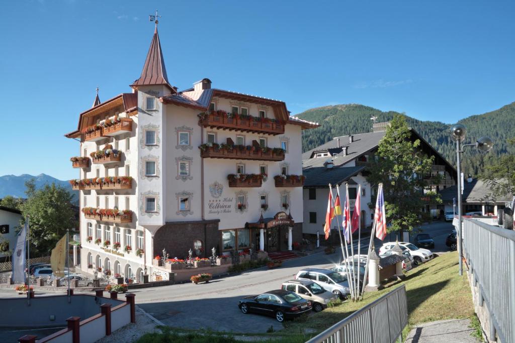 duży budynek z samochodami zaparkowanymi na parkingu w obiekcie Hotel Colbricon Beauty & Relax w mieście San Martino di Castrozza