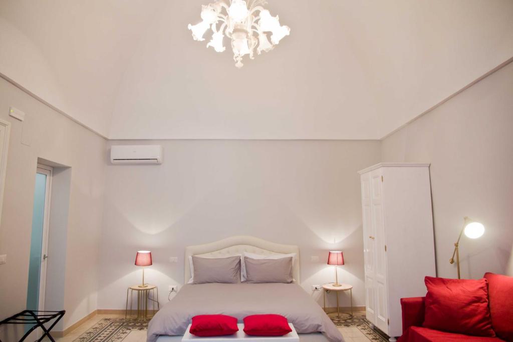 a bedroom with a white bed and a red couch at A&G House in Ceglie Messapica