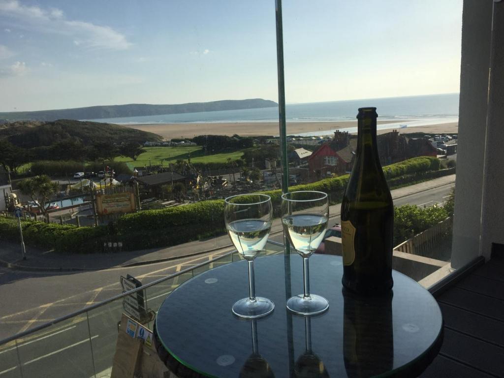 a table with two glasses and a bottle of wine at Byron, Woolacombe 7 in Woolacombe