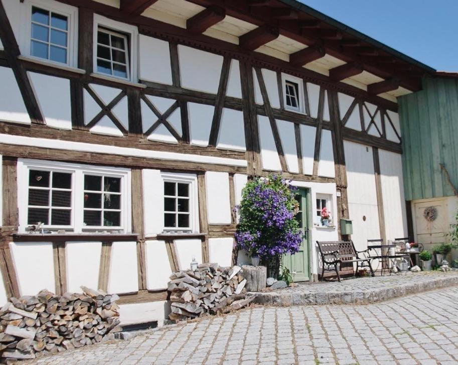 an old building with a wooden roof and a patio at Ferienwohnung Auszeit in Ausnang in Leutkirch im Allgäu