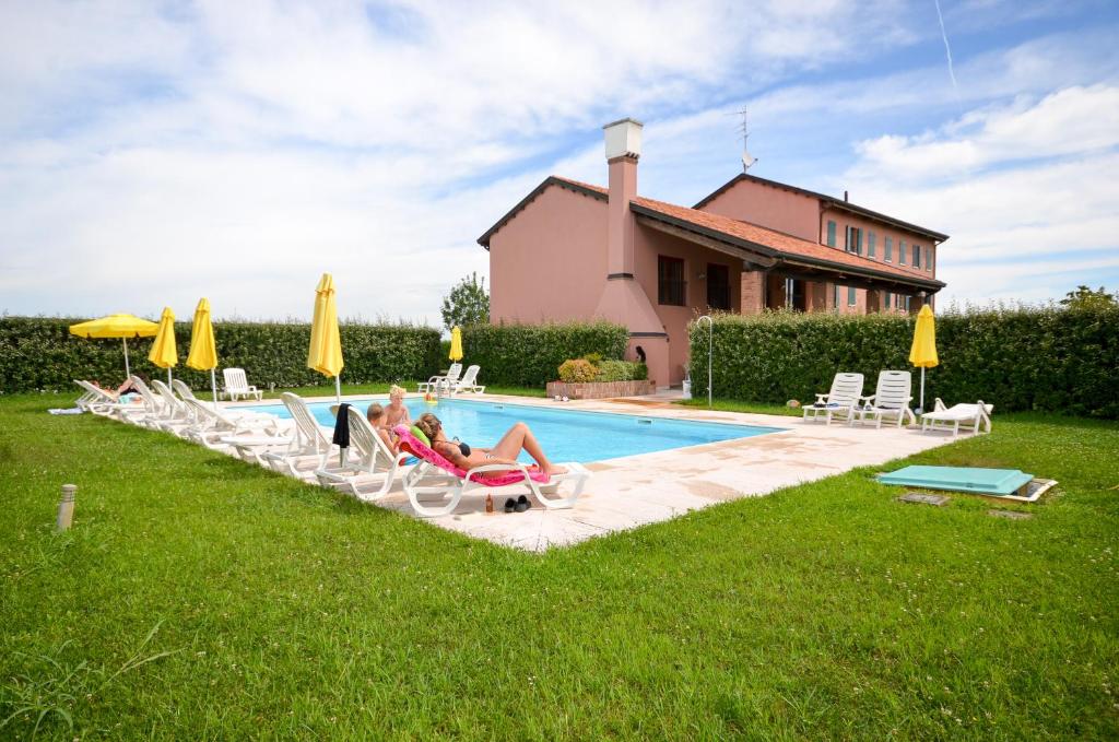 a group of people sitting in lawn chairs by a pool at Casa Miniscalchi in Marinella