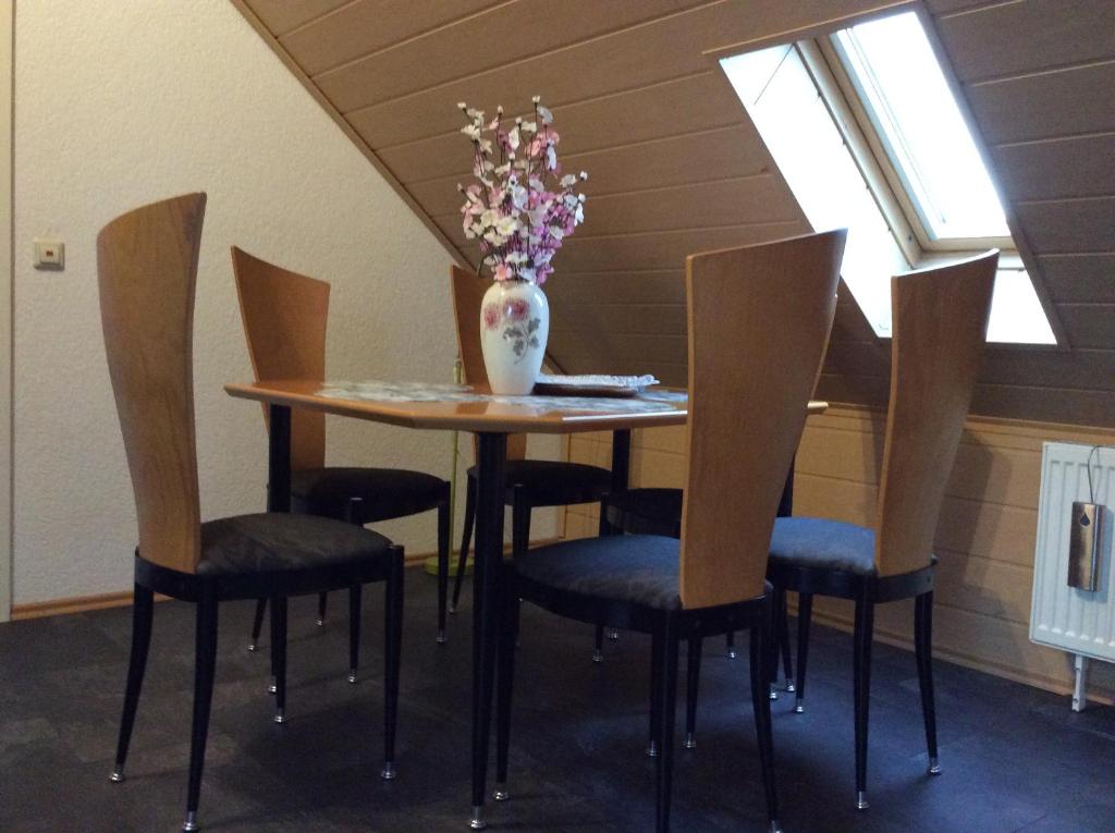een tafel met stoelen en een vaas met bloemen erop bij Apartment Jane in Bad Schonborn