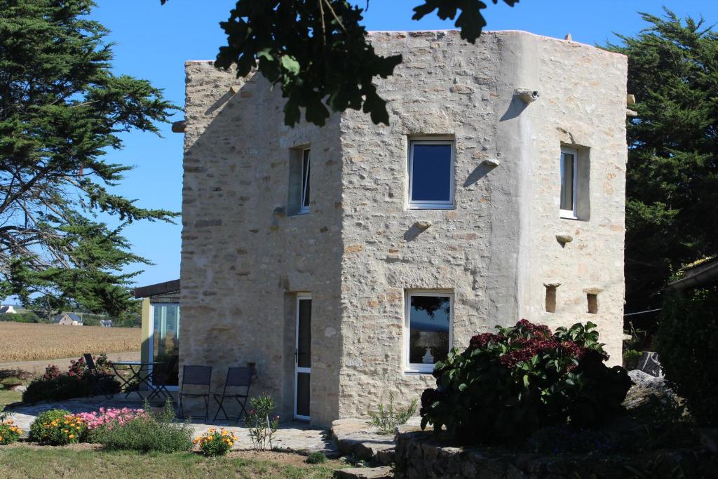 una vecchia casa in pietra con dei fiori davanti di La Tour du Bois Dormant a Plozévet