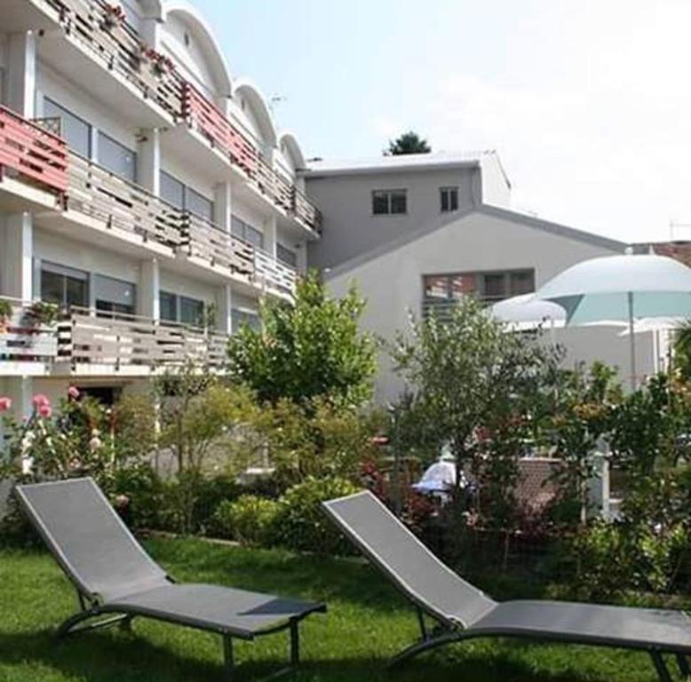 2 chaises et un parasol devant un bâtiment dans l'établissement Levante Residence, à La Spezia