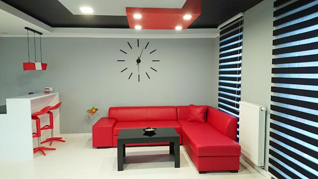 キェルツェにあるApartament Exclusive RedBlackのリビングルーム(赤いソファ、壁掛け時計付)