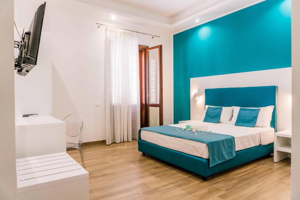 - une chambre bleue et blanche avec un lit et une télévision dans l'établissement B&B Le Tartarughe, à San Vito Lo Capo
