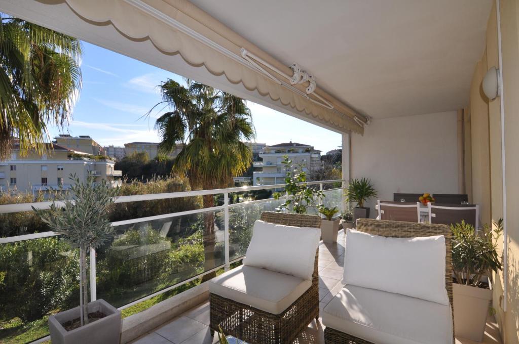 uma varanda com 2 cadeiras e uma grande janela em Elegant one-bedroom apartment with swimming pool - StayInAntibes - Le Vallon em Antibes