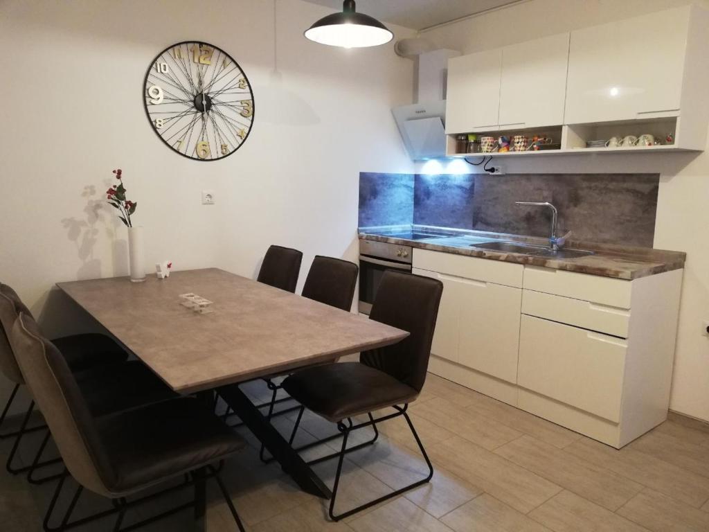 una cocina con mesa y sillas y un reloj en la pared en Apartma Stela in Terme Čatež, en Čatež ob Savi