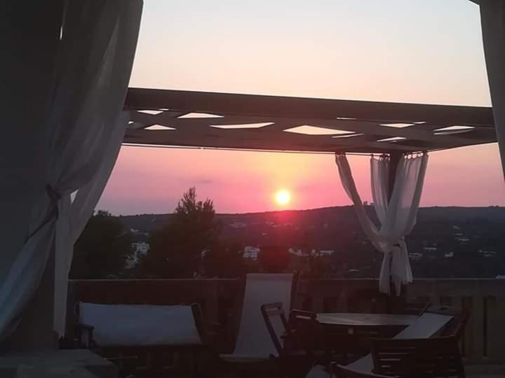 uma vista para o pôr-do-sol a partir de uma varanda com cadeiras e mesas em Villa Pedaci B&B em Leuca