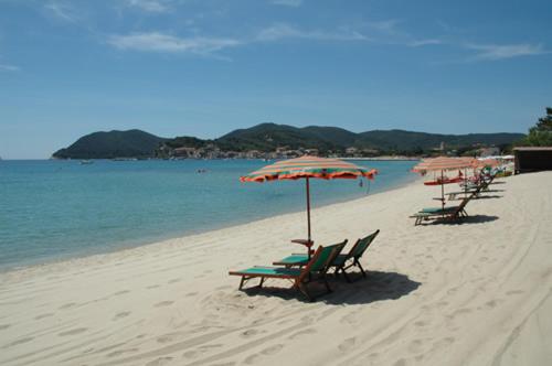 grupa leżaków i parasoli na plaży w obiekcie Appartamento elegante a Marina di Campo w mieście Campo nell'Elba