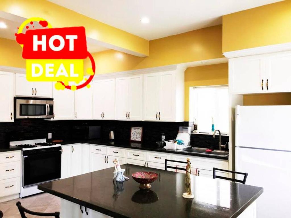a kitchen with white cabinets and a table with a hot deal sign at Hollywood Stay in Los Angeles
