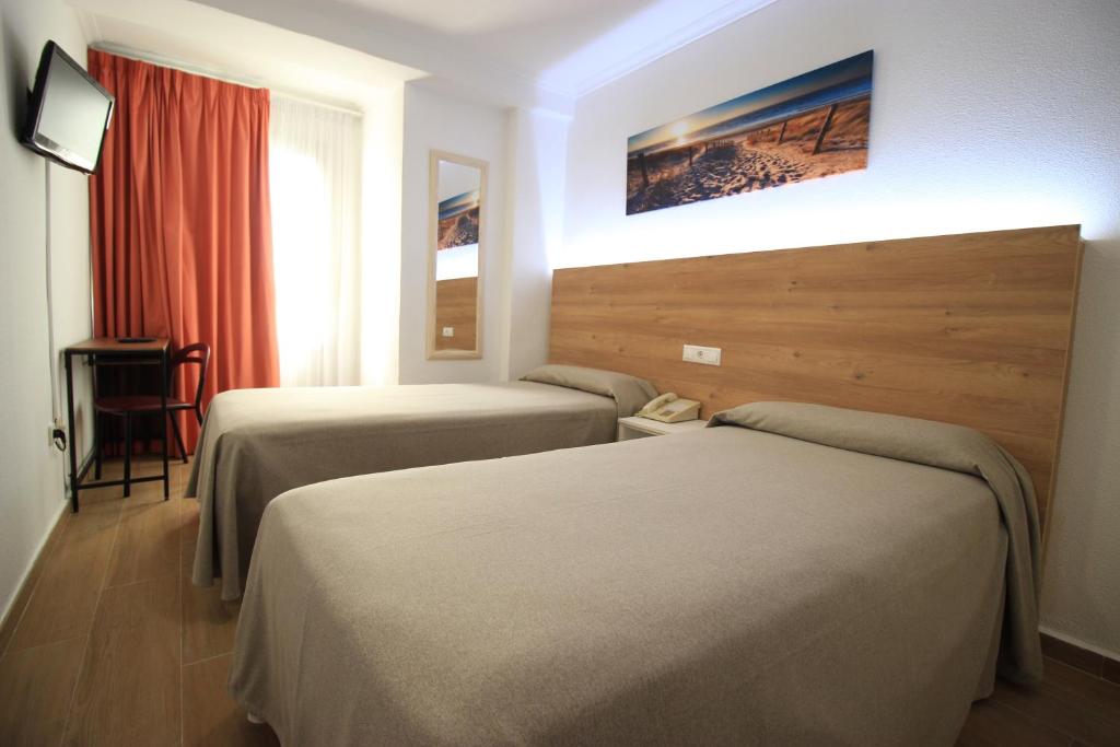 a hotel room with two beds and a chair at Hostal Pensimar in El Altet