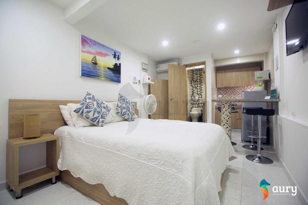 a bedroom with a white bed and a kitchen at Apartamentos Aury in San Andrés