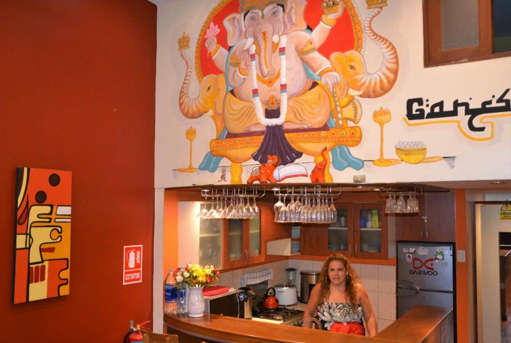 a woman standing in a kitchen with a large painting on the wall at Suspiros del Inka in Lima