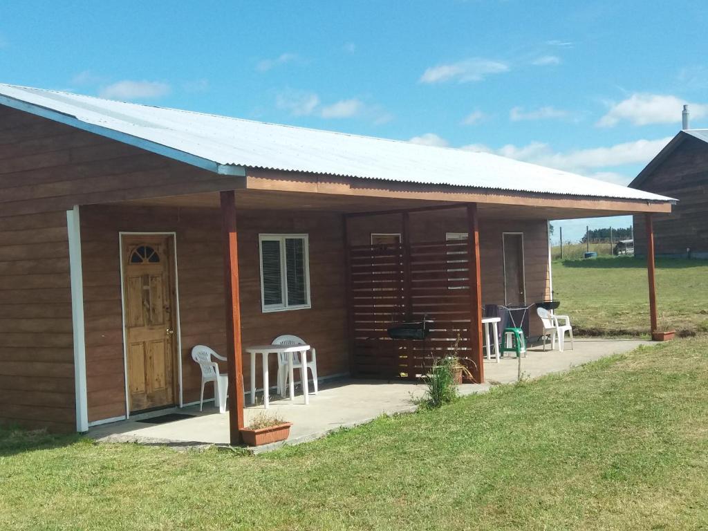 eine kleine Holzhütte mit einer Veranda und Stühlen in der Unterkunft Cabañas M y M Frutillar in Frutillar