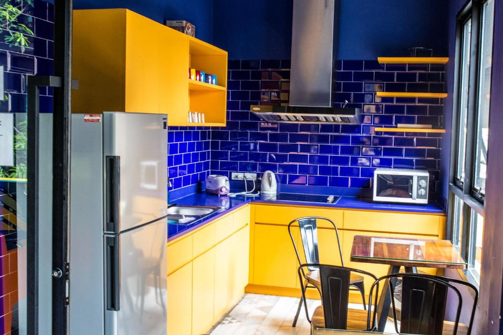a kitchen with yellow and blue walls and a refrigerator at iSanook Hostel in Bangkok