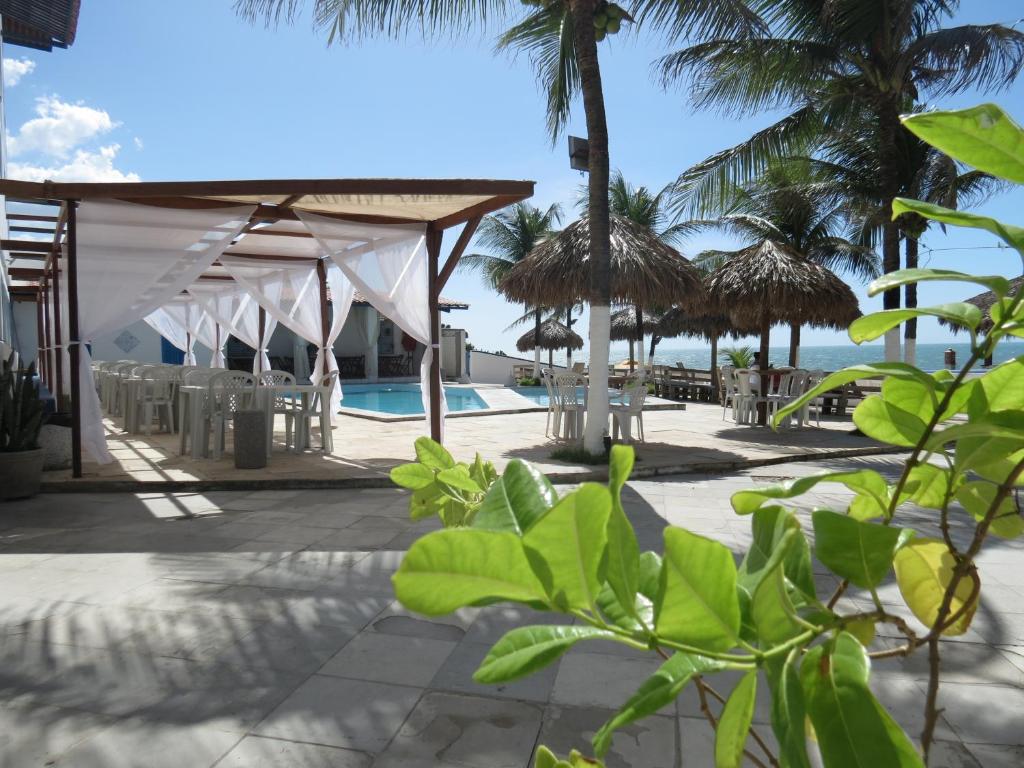 a resort with a pool and tables and palm trees at La Suite Praia Hotel in Caucaia