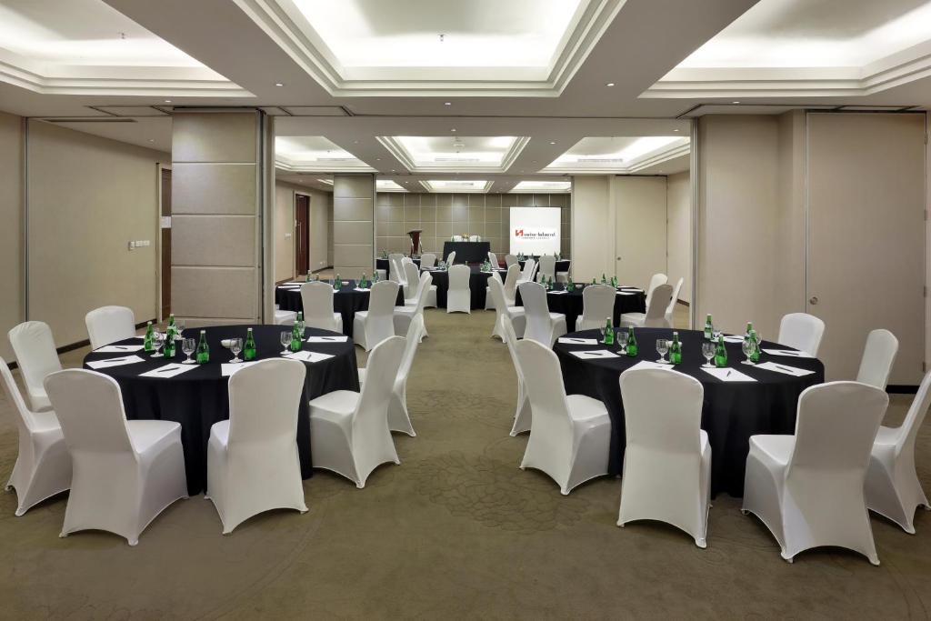 a conference room with tables and chairs and a man in a podium at Swiss-Belhotel Airport Jakarta in Tangerang