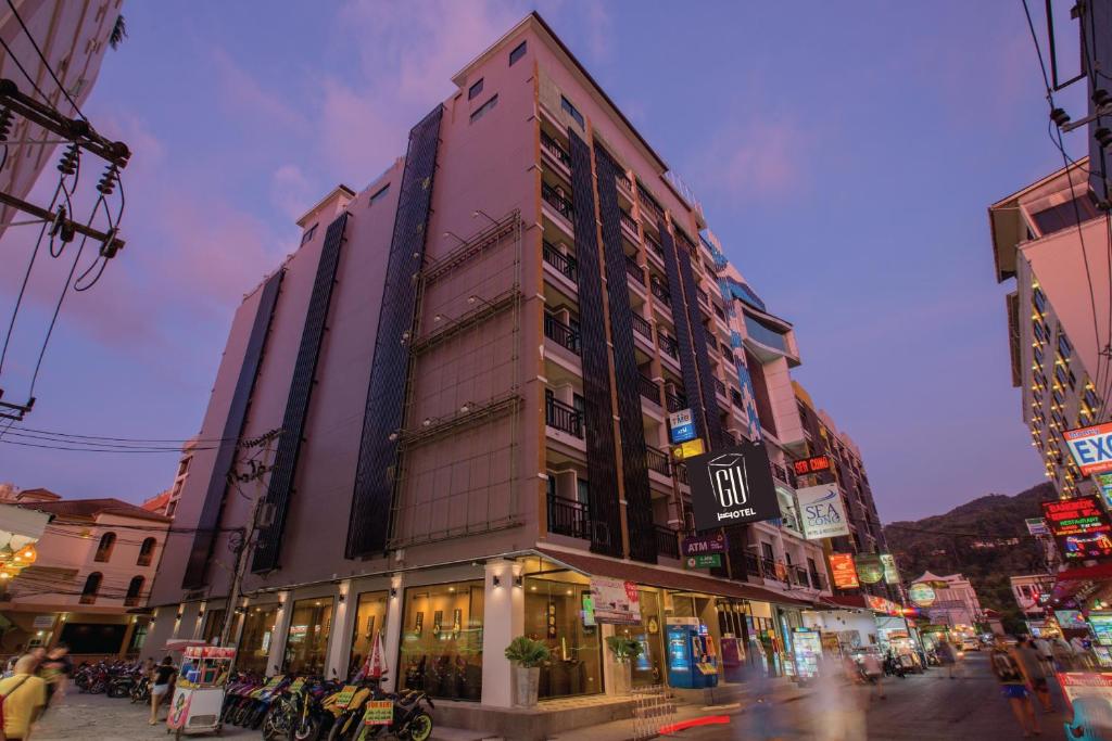 a tall building on the corner of a city street at Gu Hotel Patong in Patong Beach