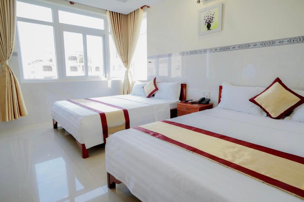 a hotel room with two beds and a window at Binh Minh Hotel in Vung Tau