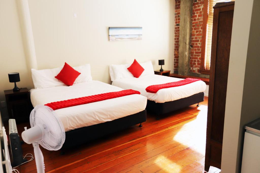 two beds with red pillows in a room at Aura Hotel in Wellington