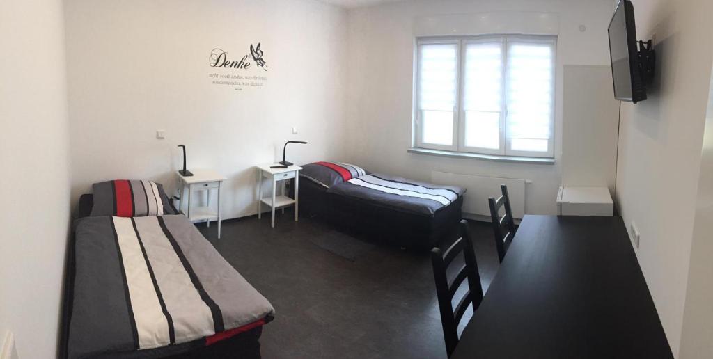 een kamer met 2 bedden, een bureau en een raam bij Zimmervermietung Dietzenbach in Dietzenbach