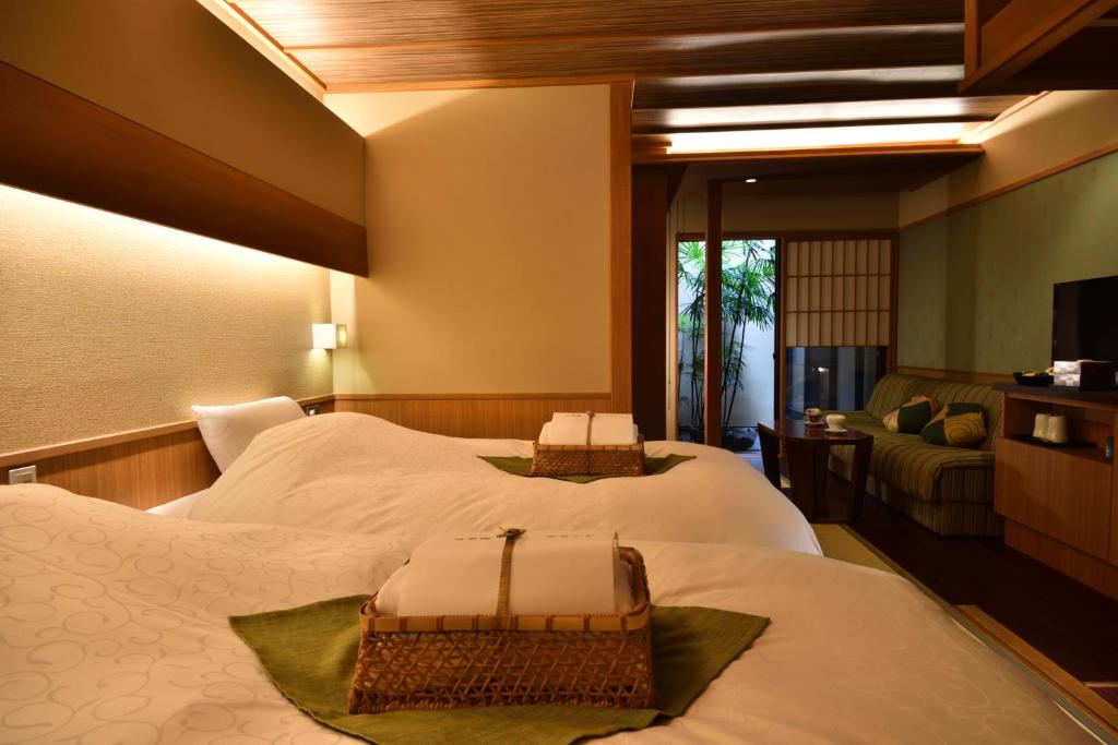 京都市にある京小宿 八坂 ゆとねのベッド2台とテレビが備わるホテルルームです。