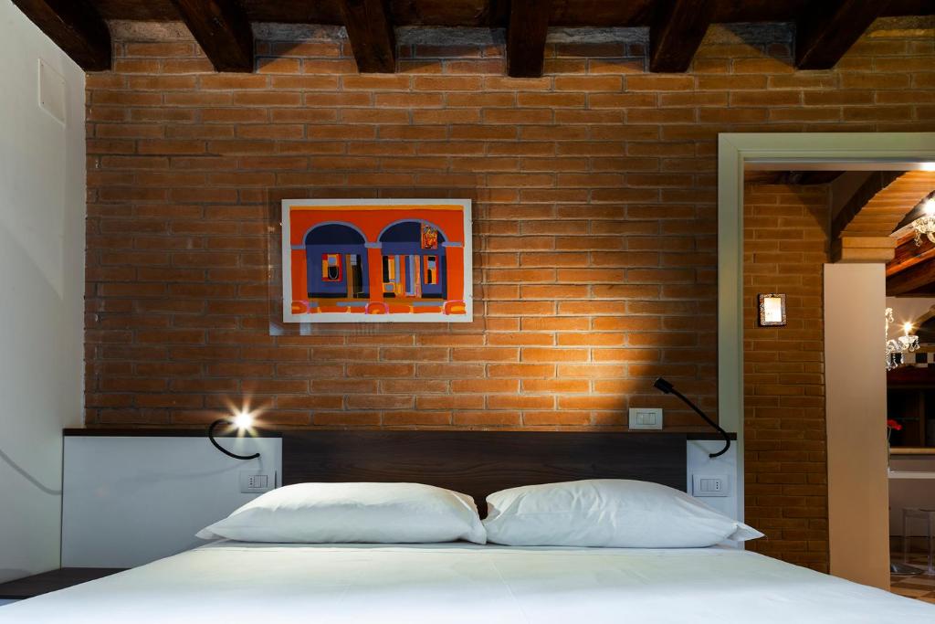 ein Schlafzimmer mit einer Ziegelwand und einem Bett mit zwei Kissen in der Unterkunft Antico Caminetto alla Biennale in Venedig