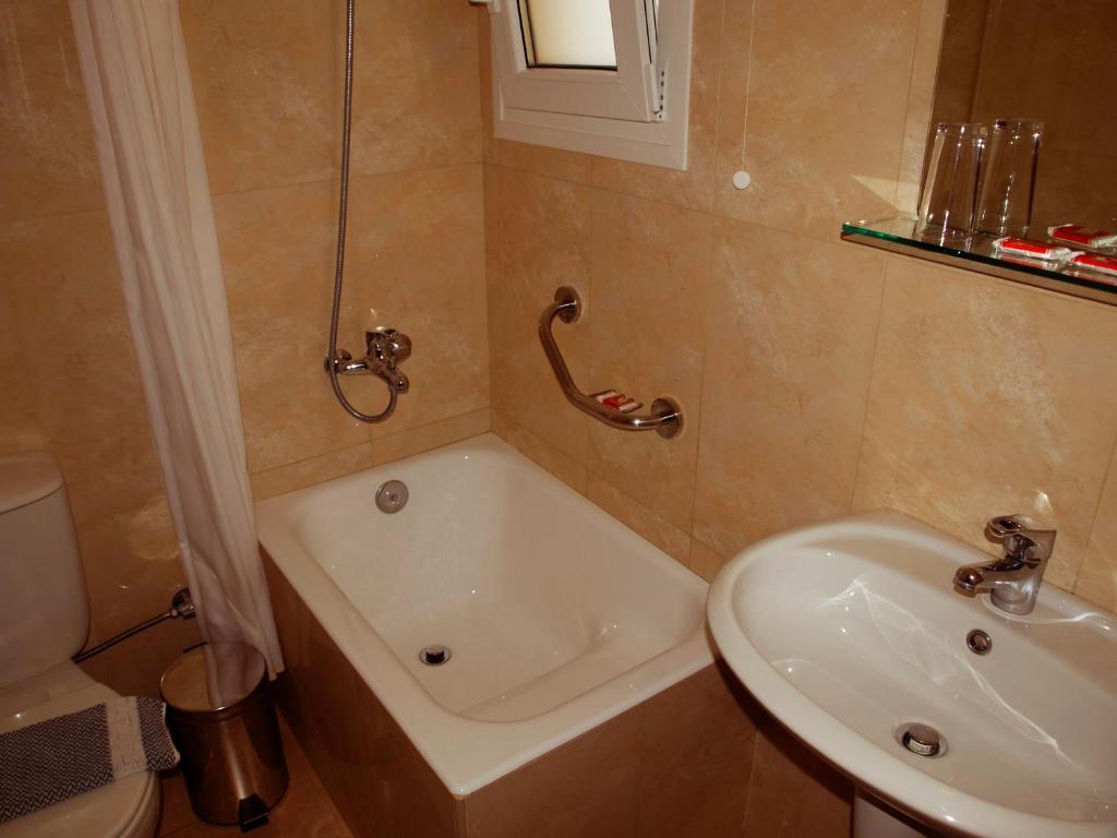 a bathroom with a sink and a tub and a toilet at Kissamos Hotel in Kissamos