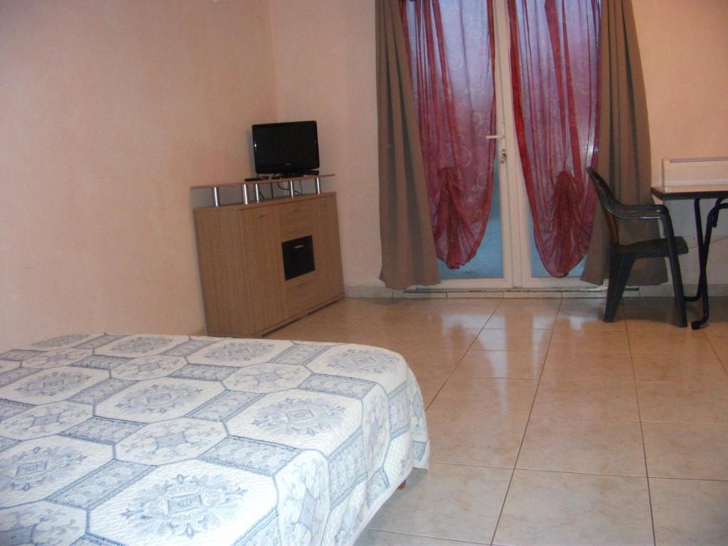 a bedroom with a bed and a television and a table at Hôtel Restaurant de la Gare (Studios Du Breuil) in La Roche-Posay