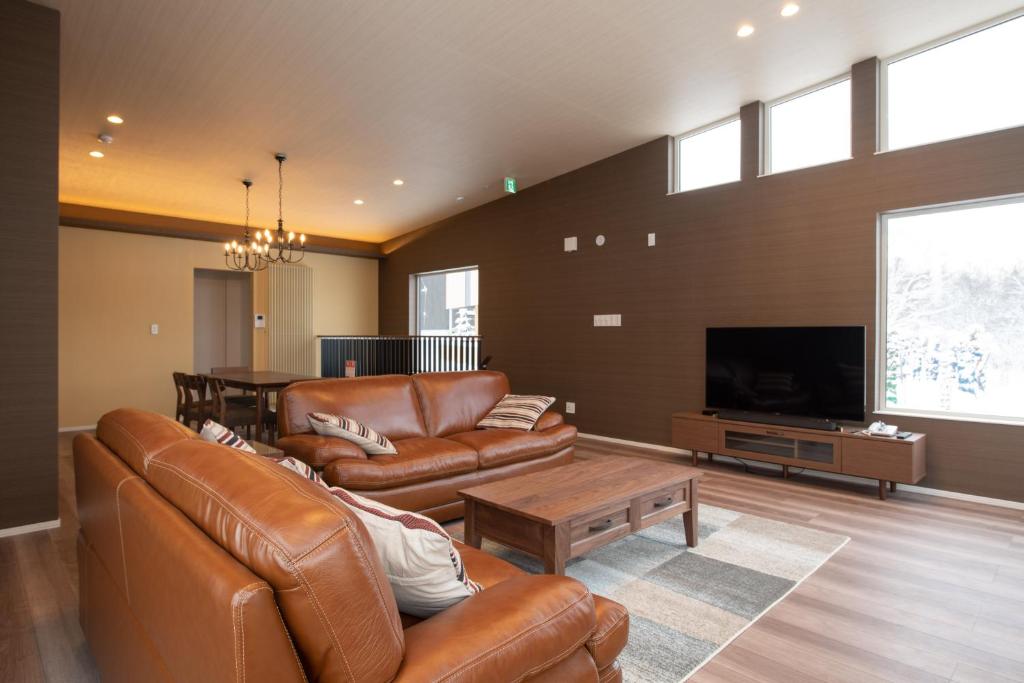 a living room with leather furniture and a flat screen tv at Mountain Butterfly in Niseko